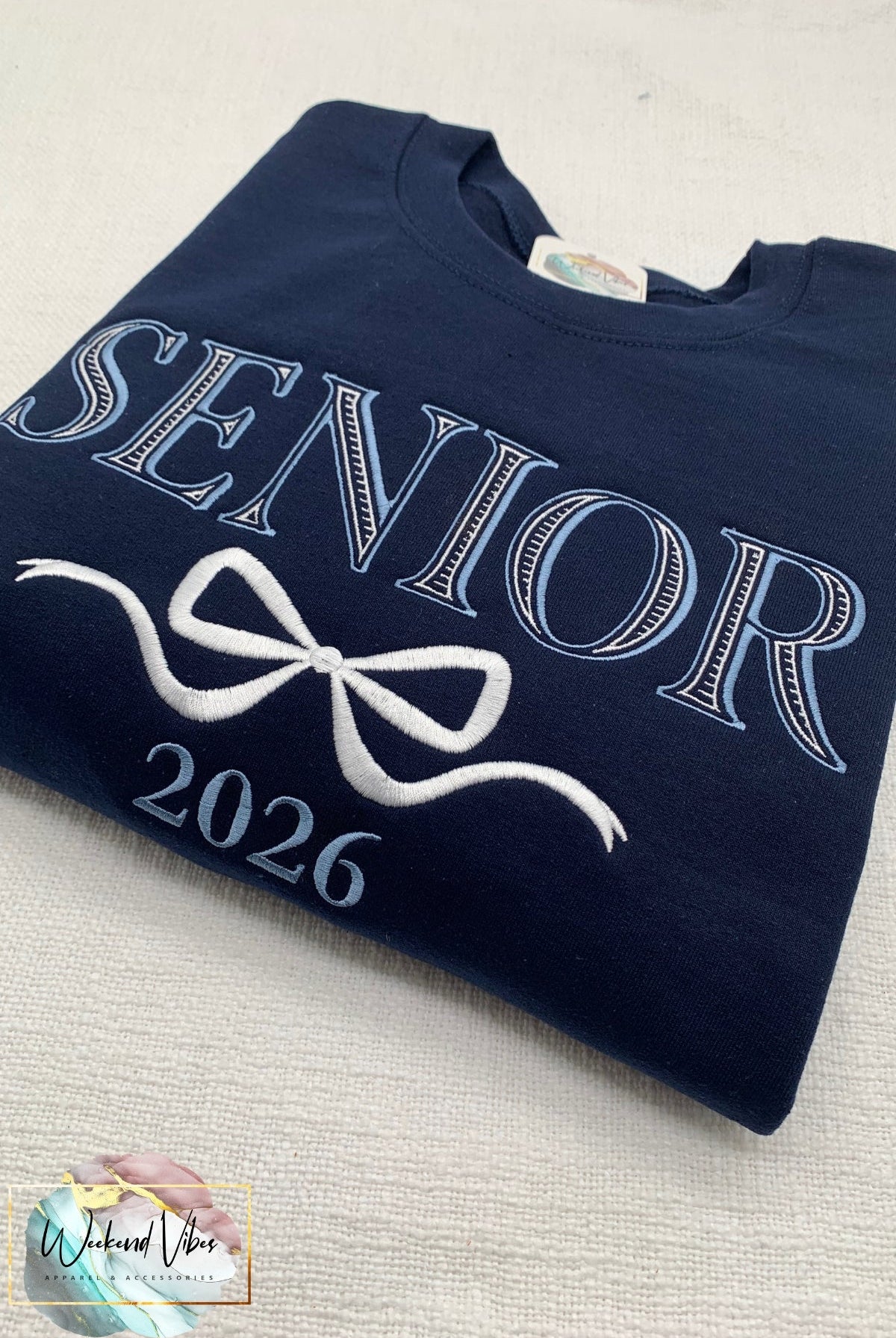 Navy blue sweatshirt with 'Senior 2026' text on a light gray surface