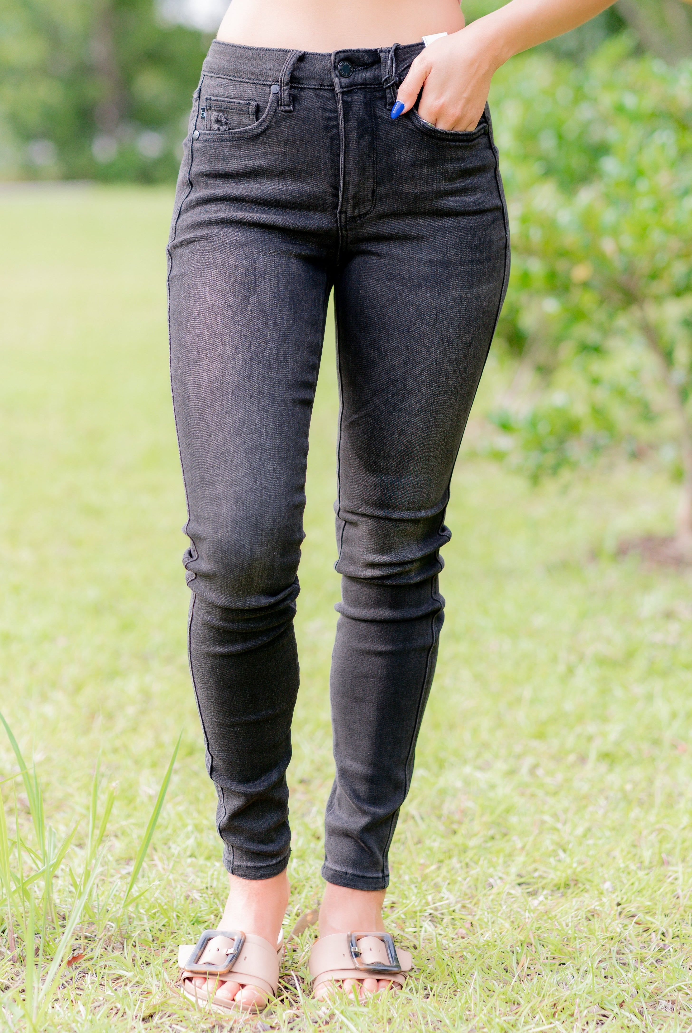 Person wearing black skinny jeans standing in a grassy area