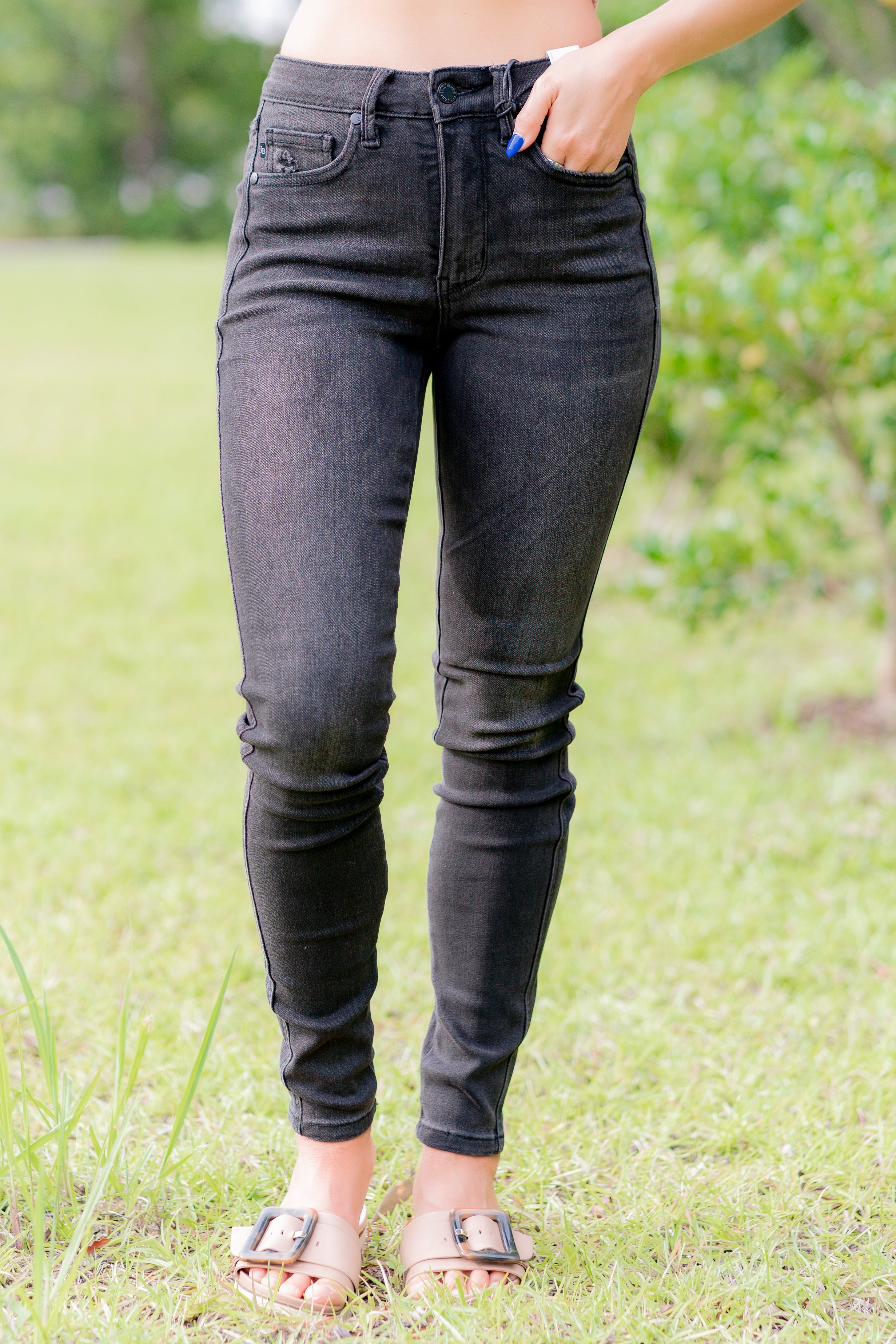 Person wearing black skinny jeans standing in a grassy area