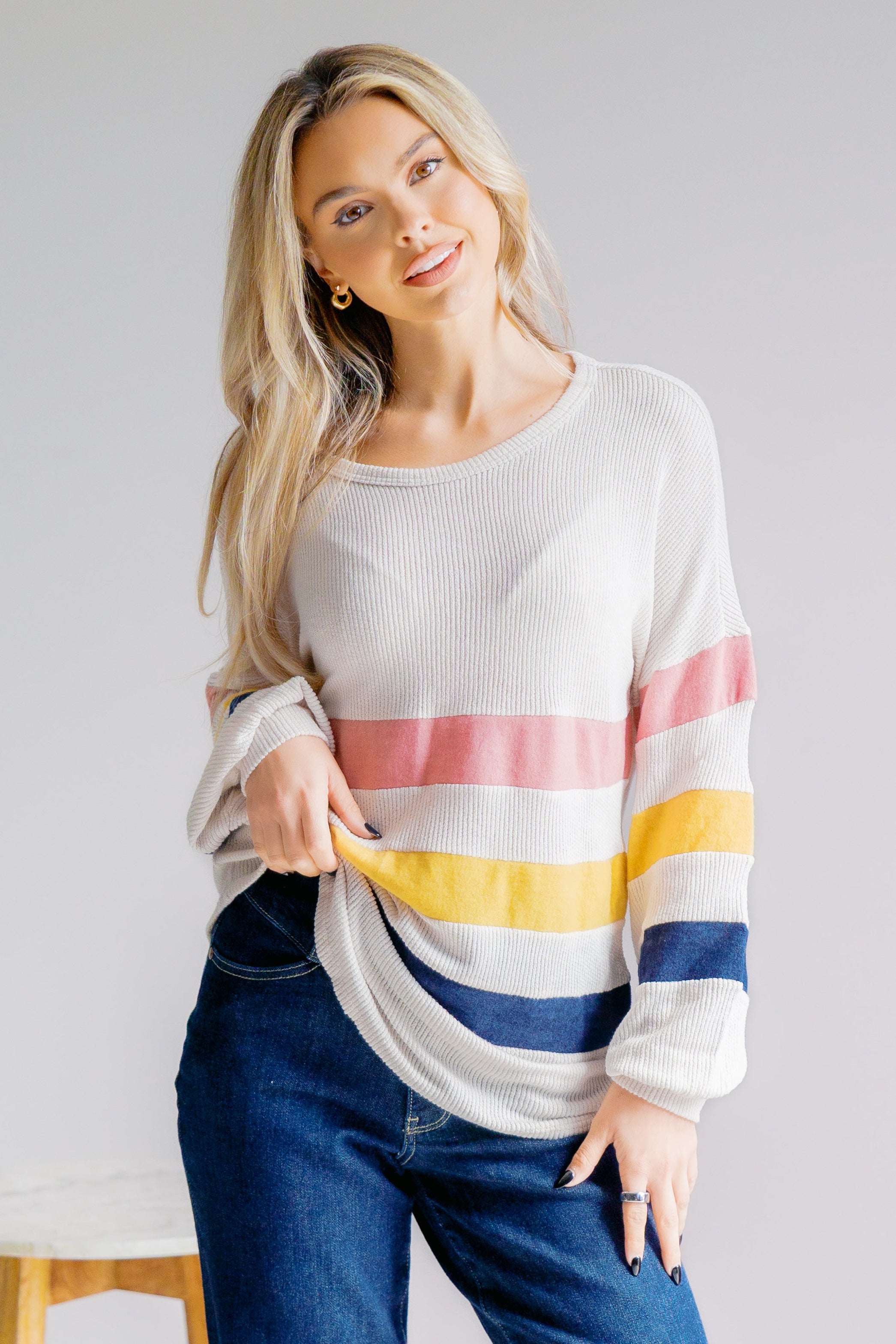 Woman wearing a colorful striped sweater with a plain background