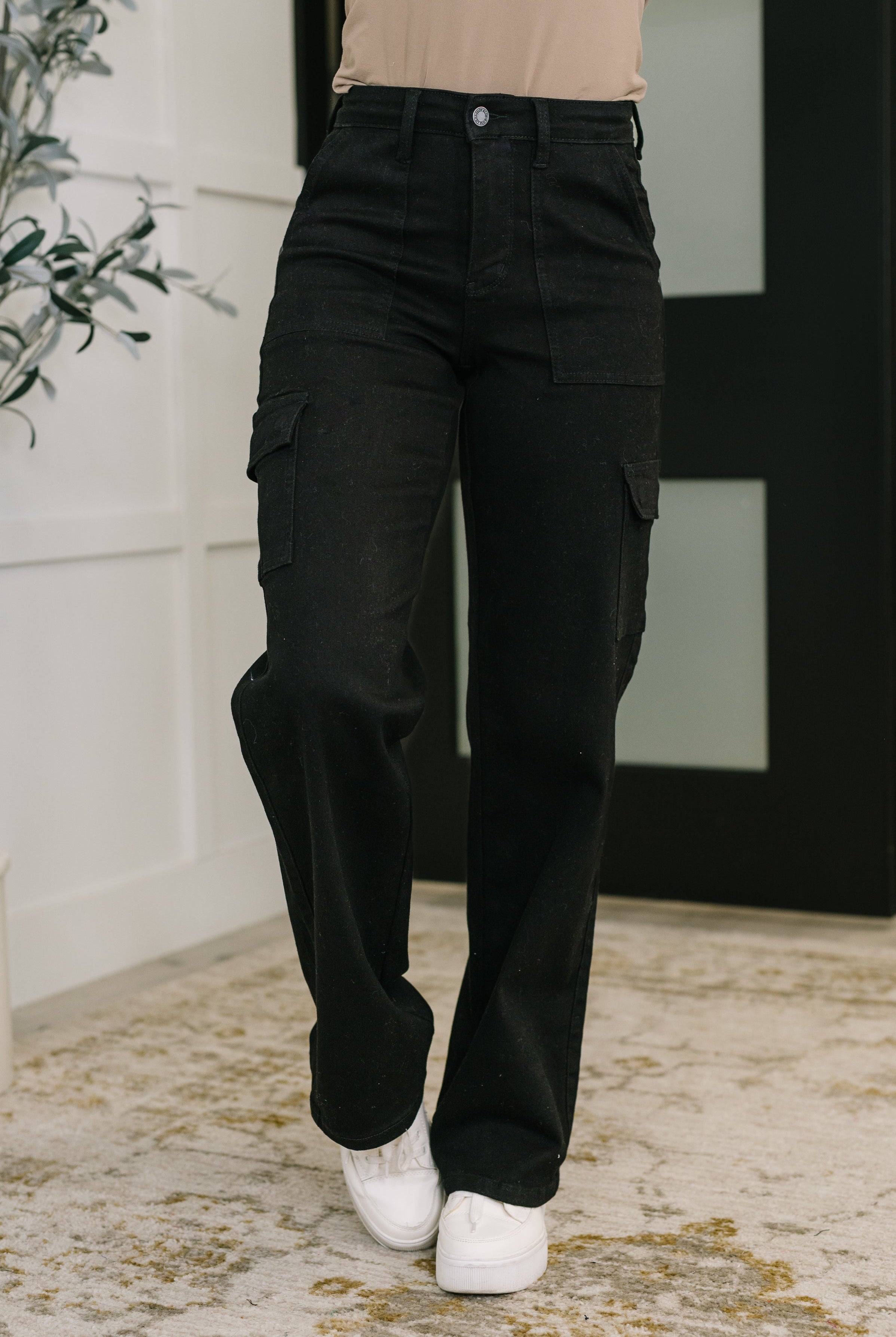 Person wearing black cargo pants with a neutral background