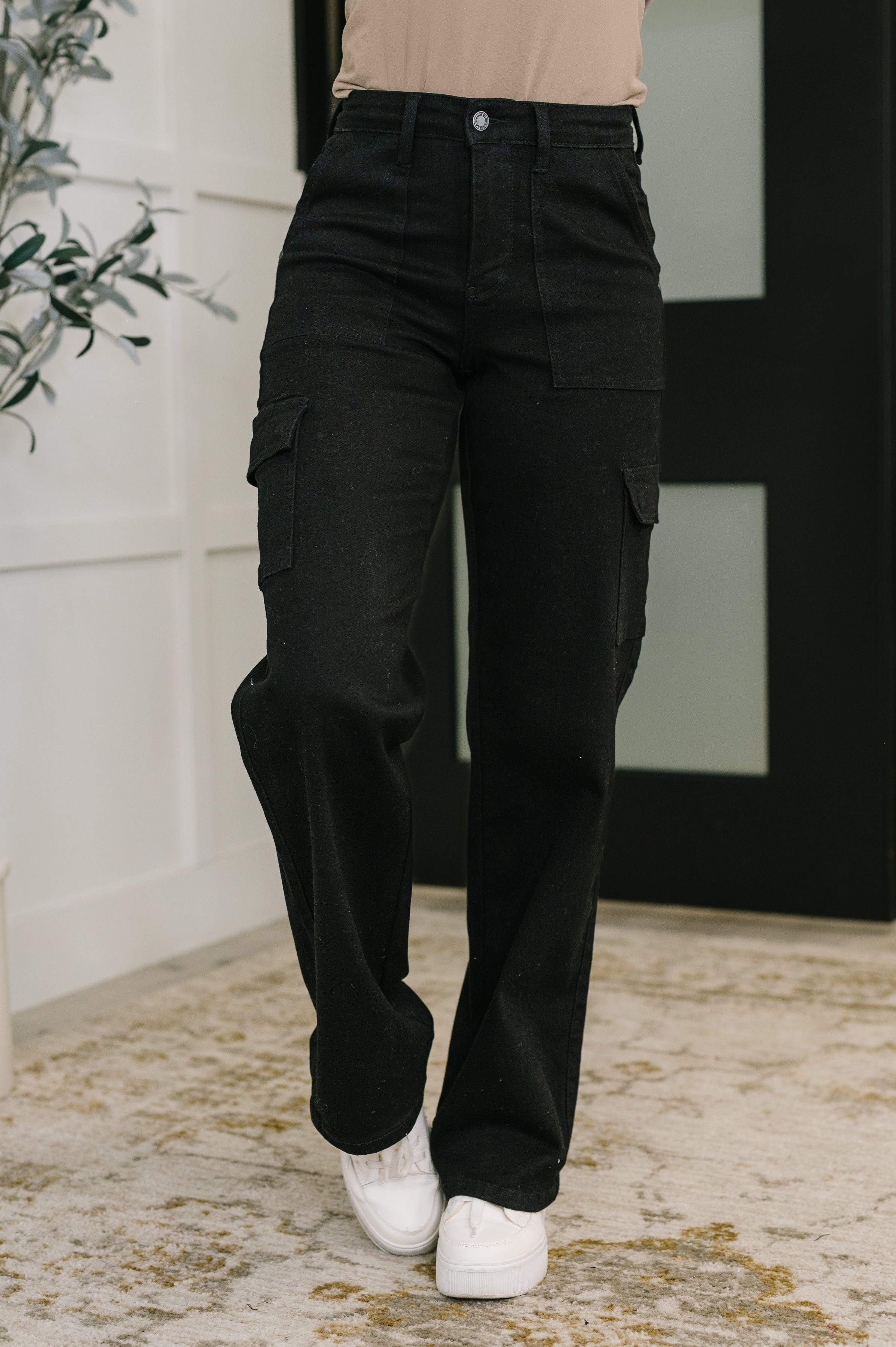 Person wearing black cargo pants with a neutral background