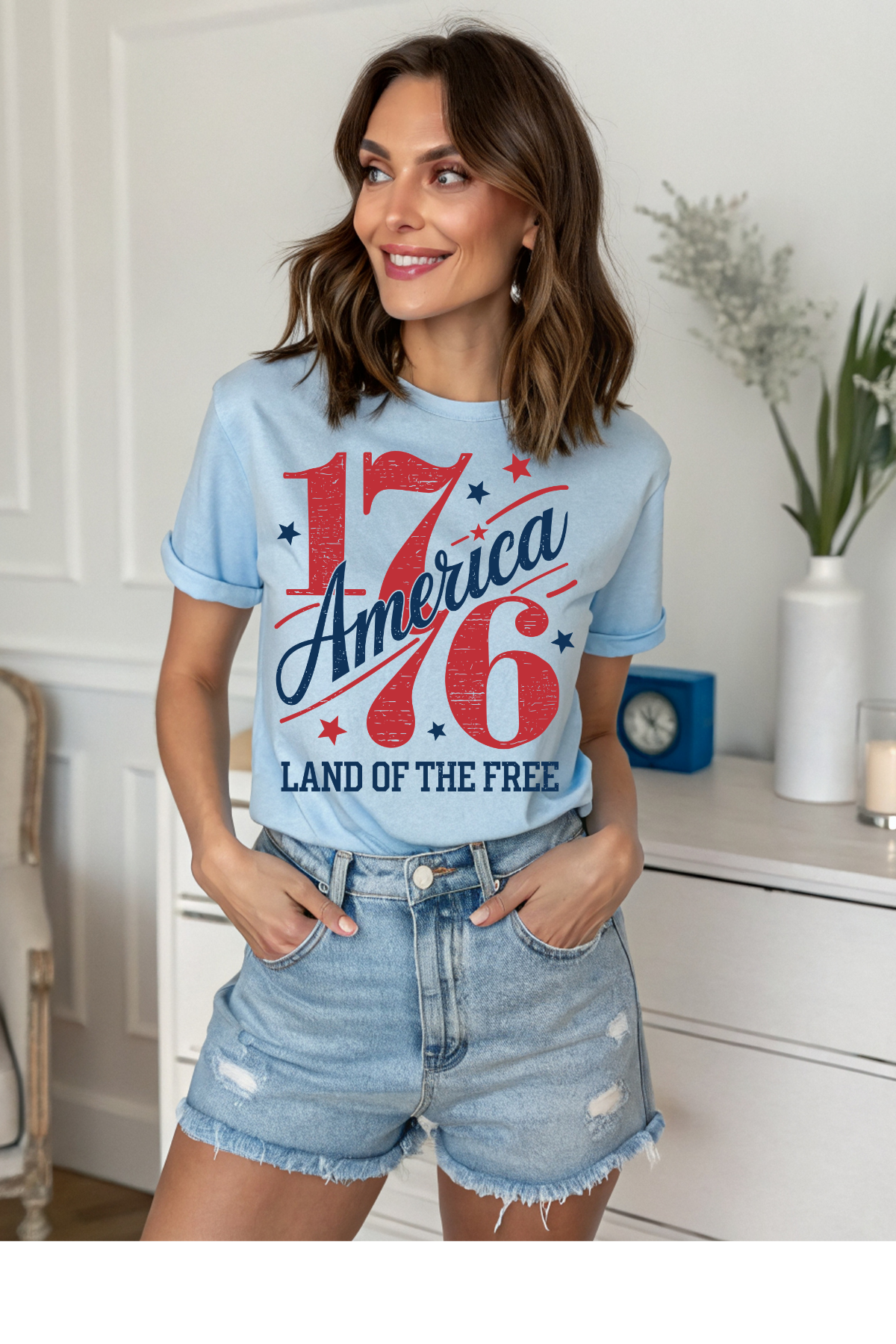 Woman wearing a light blue t-shirt with '1776 America Land of the Free' design in a room.