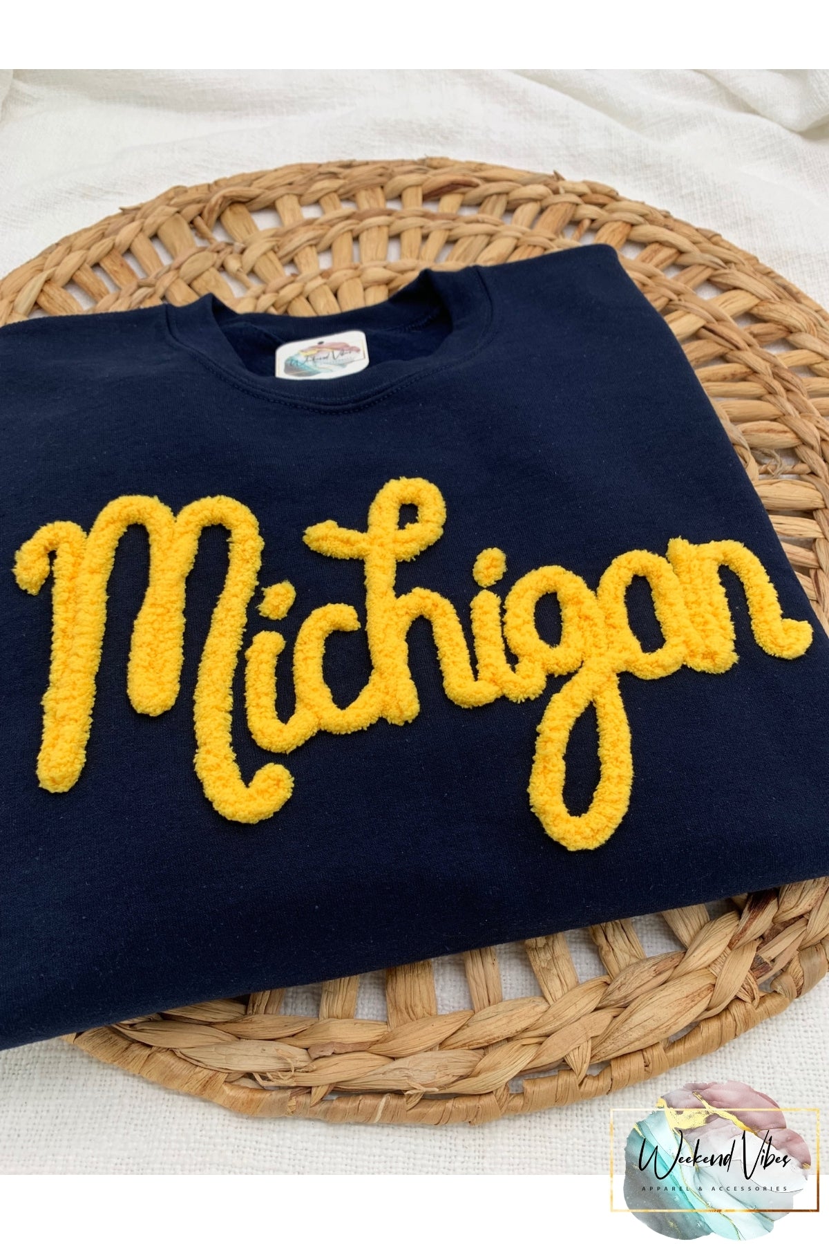 Navy sweatshirt with yellow 'Michigan' text on a woven mat
