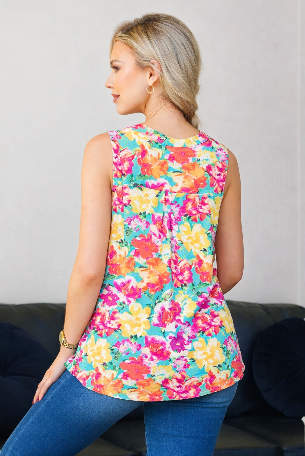 Woman wearing a colorful floral sleeveless top against a neutral background