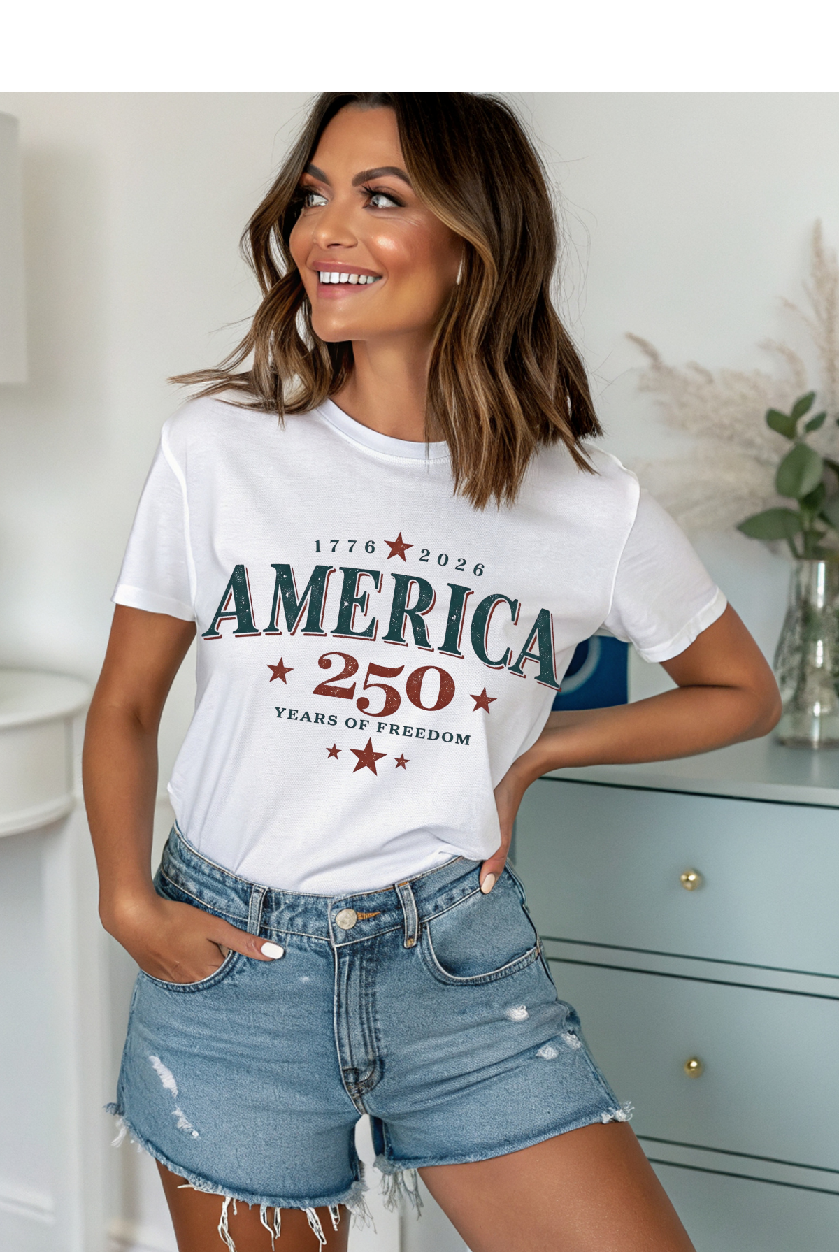 Woman wearing a white t-shirt with 'AMERICA 250' design and denim shorts indoors.