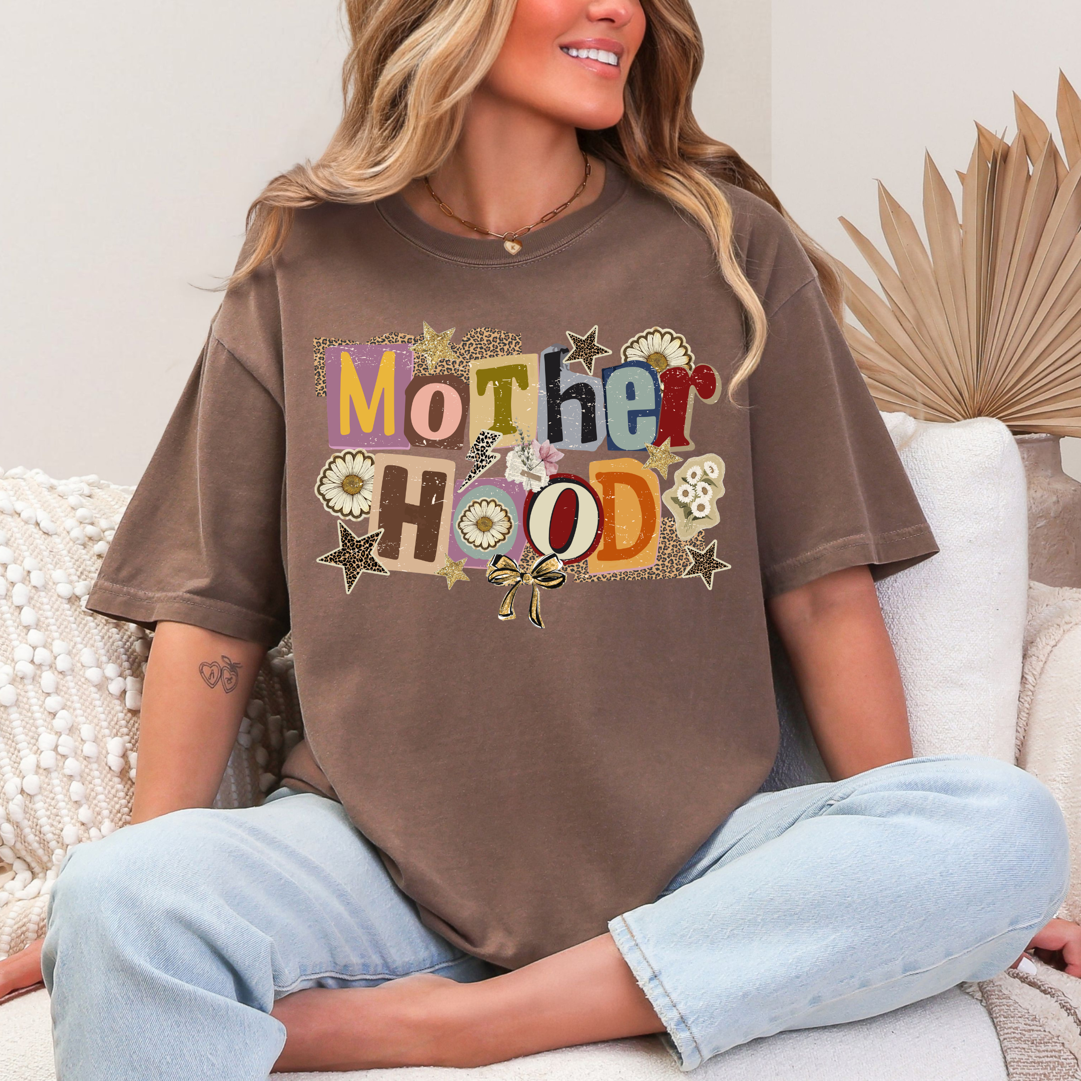 Woman wearing a brown t-shirt with 'Mother Hood' printed on it, sitting on a couch.