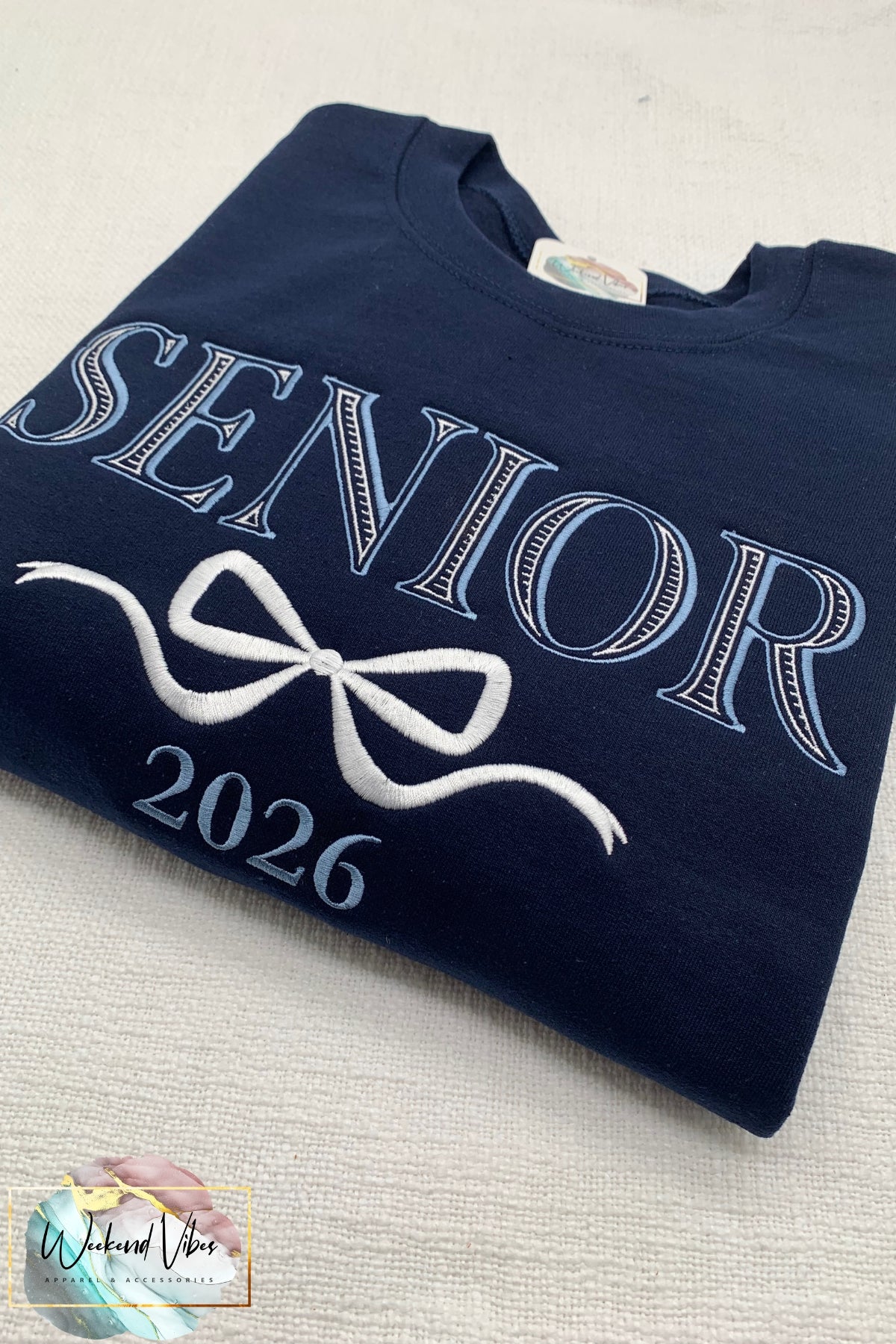 Navy blue sweatshirt with 'Senior 2026' text on a light gray surface