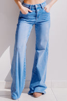 Woman wearing light blue flared jeans against a white background