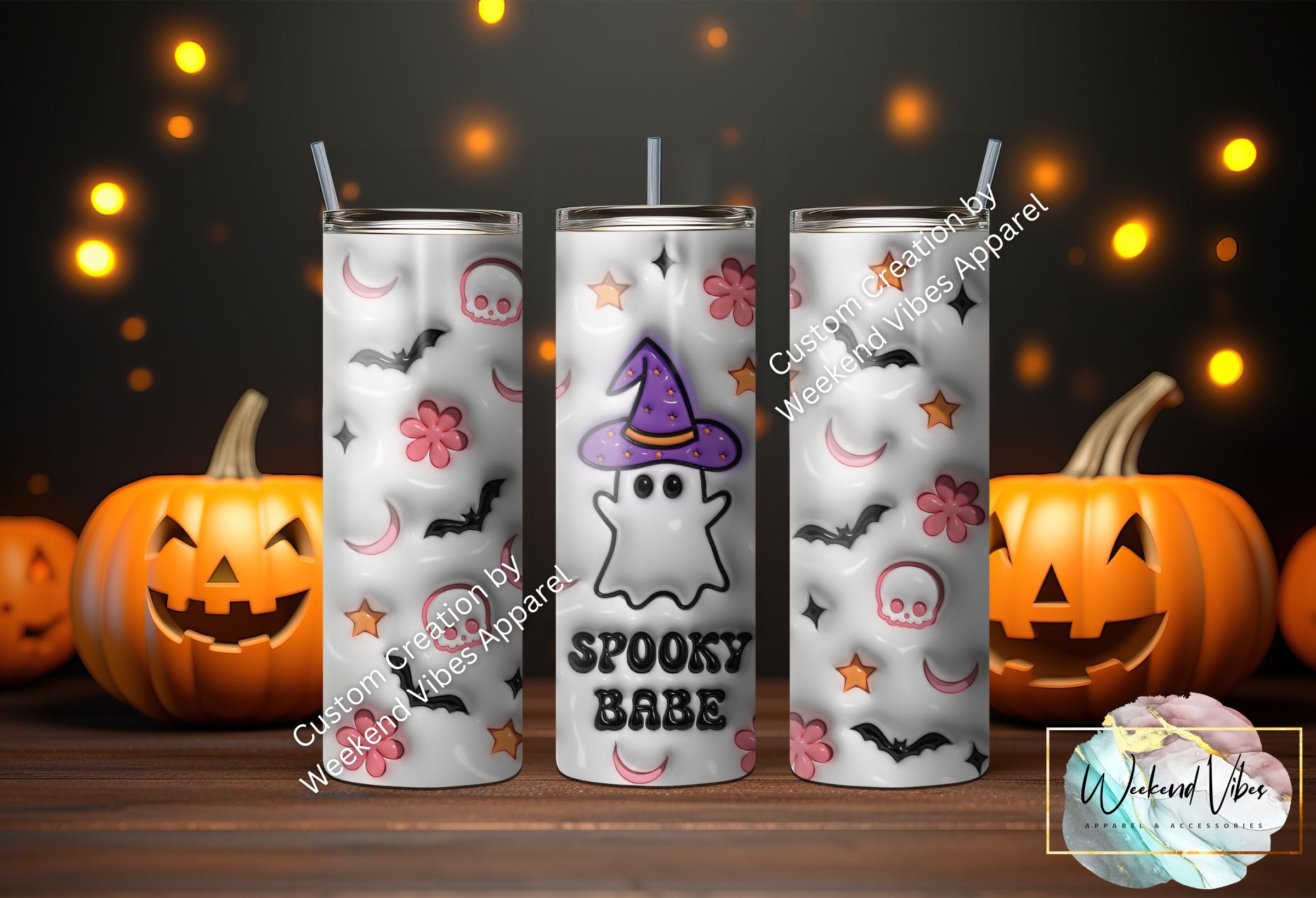 A set of three Spooky Babe Ghost Tumblers with Halloween-themed designs, including elements like bats, moons, and skulls, displayed in front of pumpkin lights.