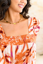 Woman wearing a colorful floral top with a blurred background