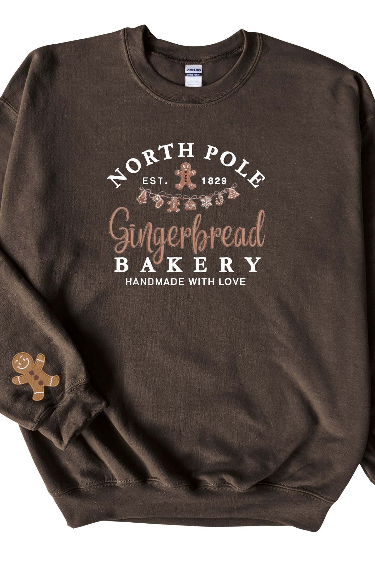 A chocolate brown sweatshirt with 'North Pole Gingerbread Bakery' embroidered on the chest and a small embroidered gingerbread man on the right sleeve.