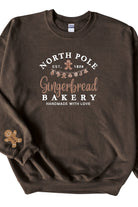 A chocolate brown sweatshirt with 'North Pole Gingerbread Bakery' embroidered on the chest and a small embroidered gingerbread man on the right sleeve.