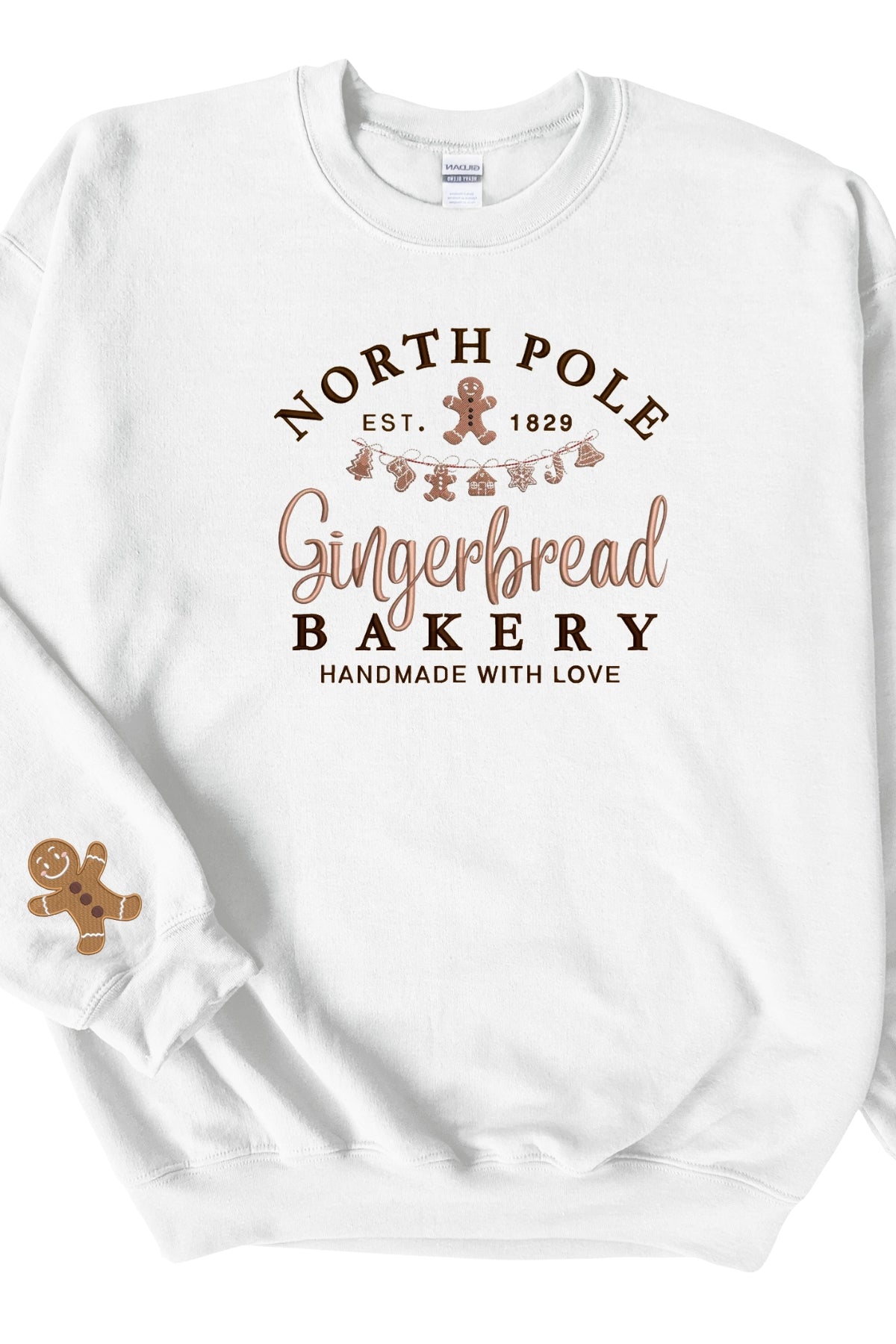 A white sweatshirt with 'North Pole Gingerbread Bakery' embroidered on the chest and a small embroidered gingerbread man on the right sleeve.