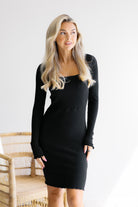 Woman wearing a black long-sleeve dress against a white background