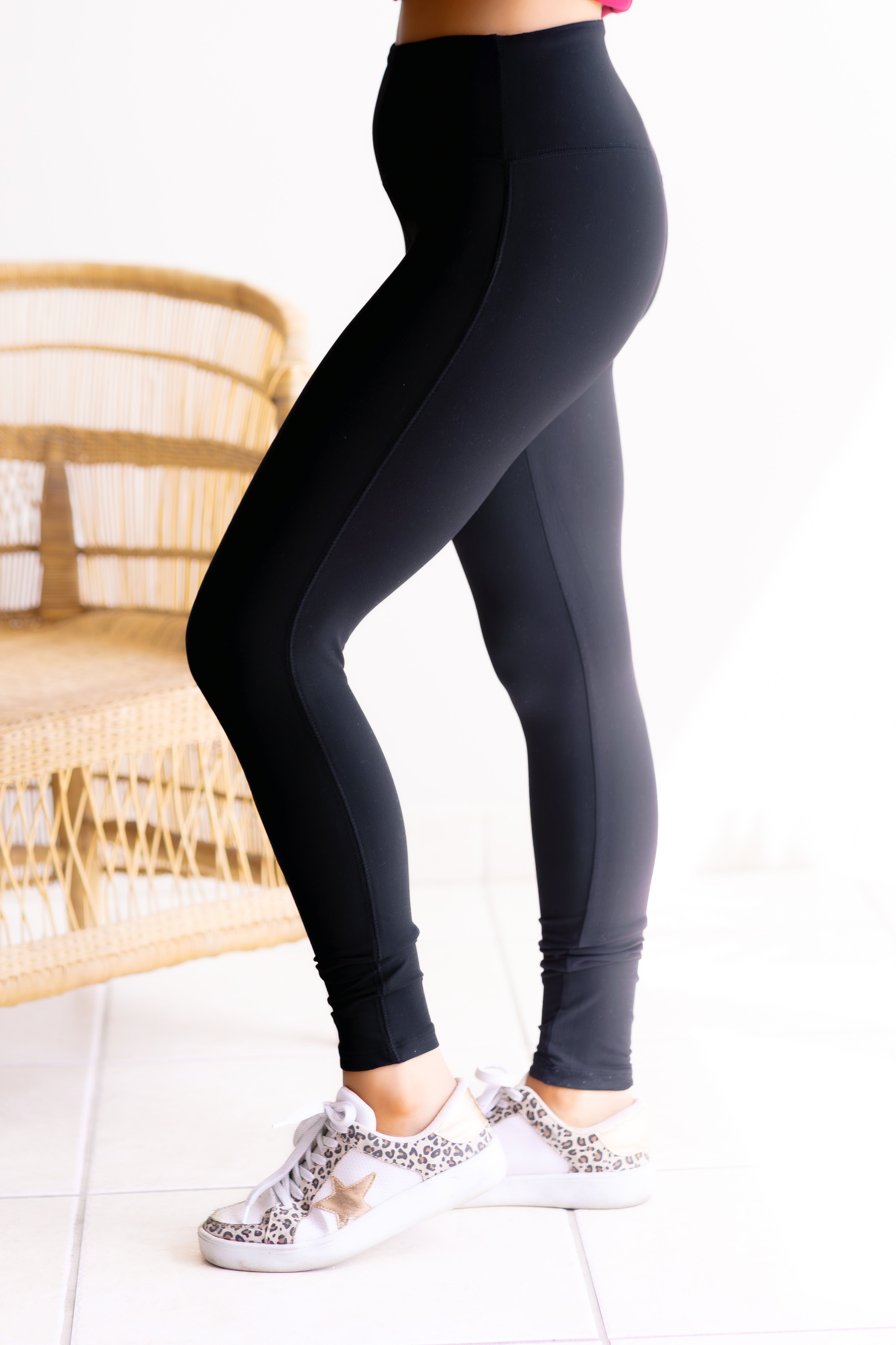 Person wearing black leggings with white sneakers in a minimal indoor setting