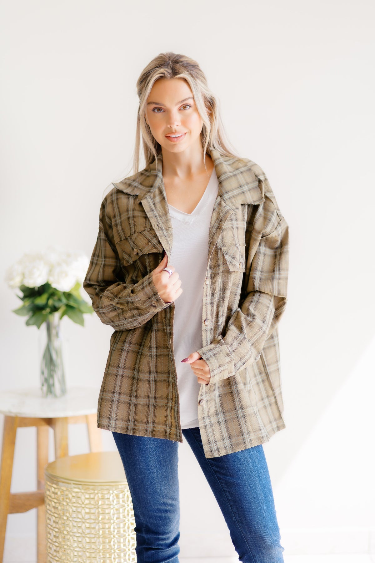 Woman wearing a plaid jacket in a minimal indoor setting