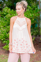 Woman wearing a white lace top with floral embroidery outdoors