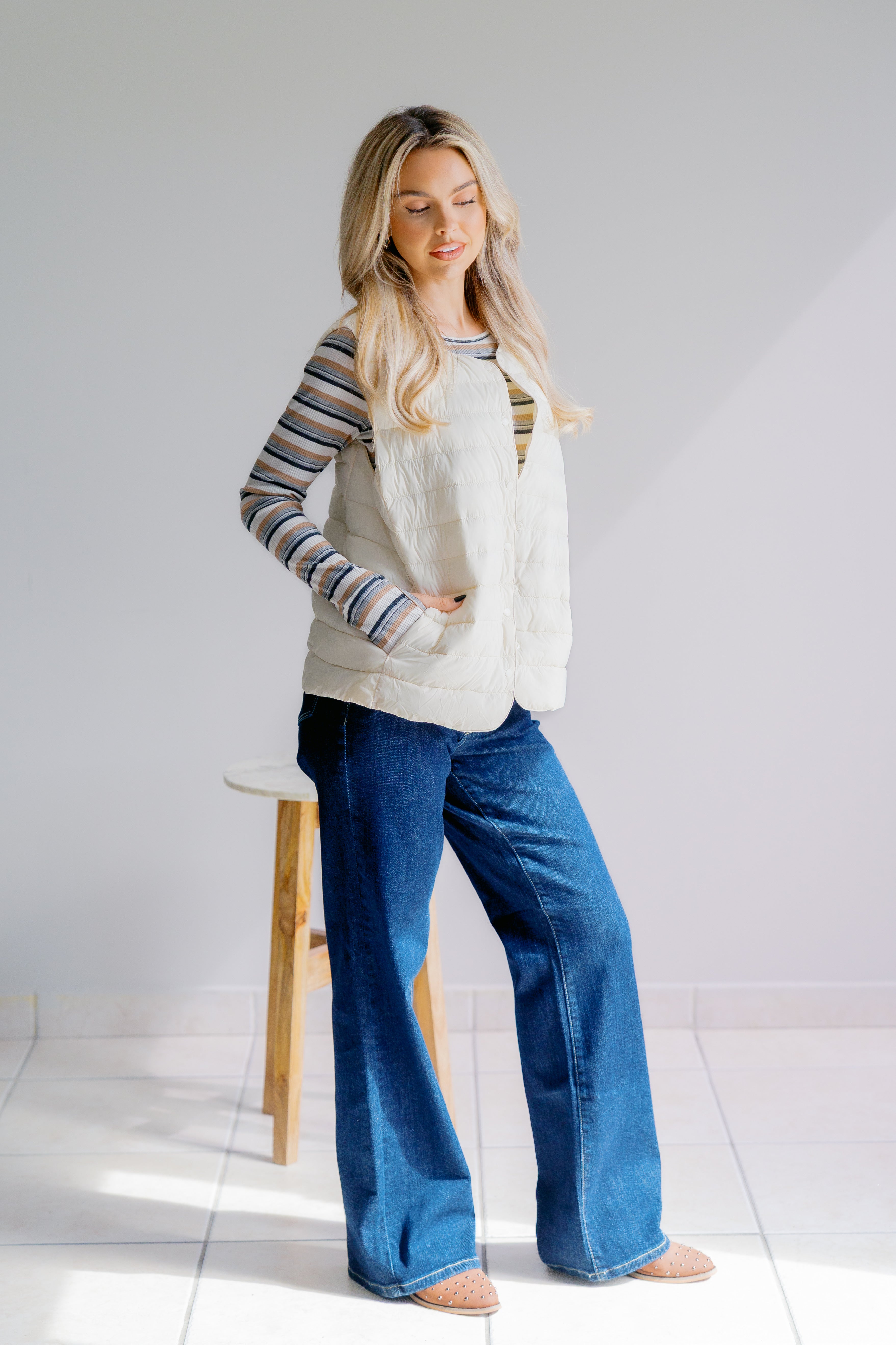 Woman wearing a striped sweater and blue jeans standing against a white background