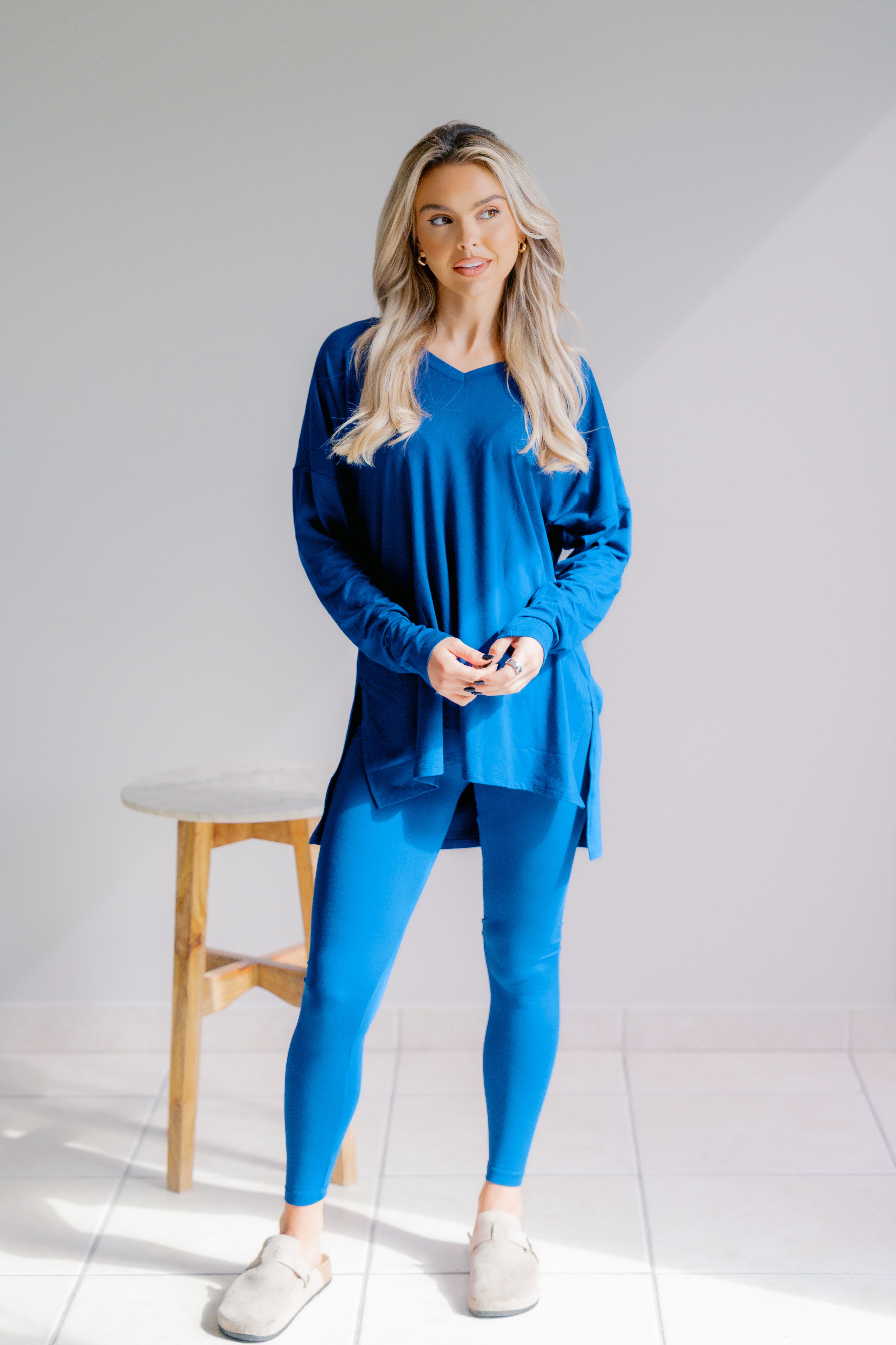 Woman wearing a blue outfit standing in a minimalistic room with a white background