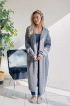 Woman wearing a long gray cardigan in a modern indoor setting