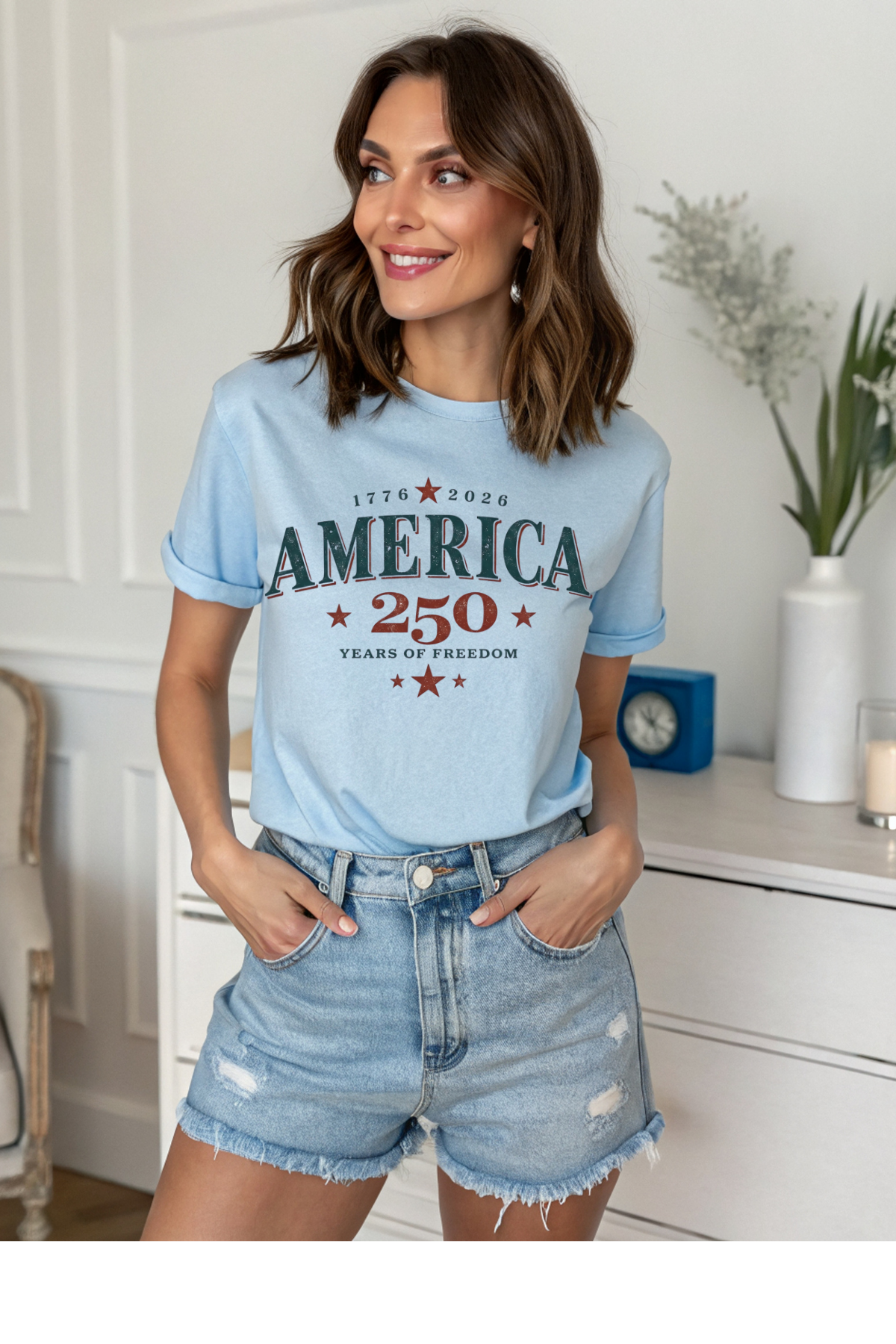 Woman wearing a light blue t-shirt with 'America 250' text in a home setting.
