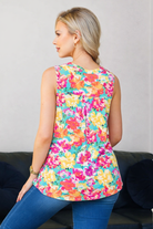 Woman wearing a colorful floral sleeveless top against a neutral background