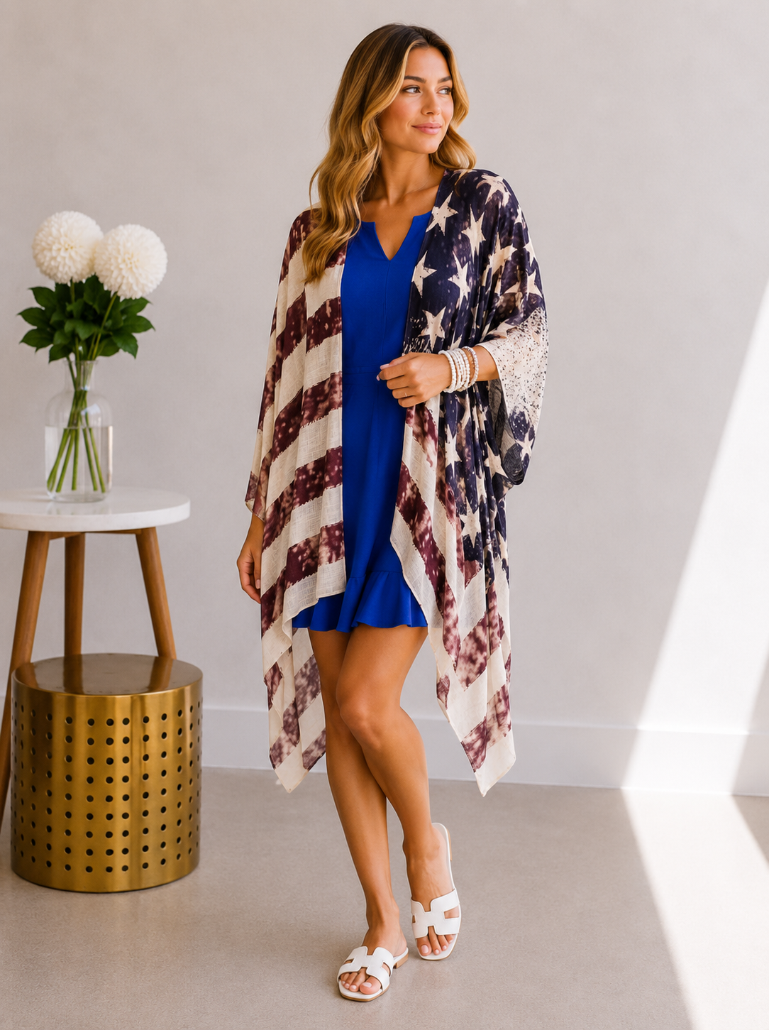 Woman wearing a blue dress with an American flag patterned cover-up in a room.
