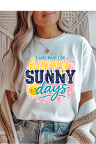 Person wearing a white t-shirt with 'I was made for happy sunny days' text and sun graphic.