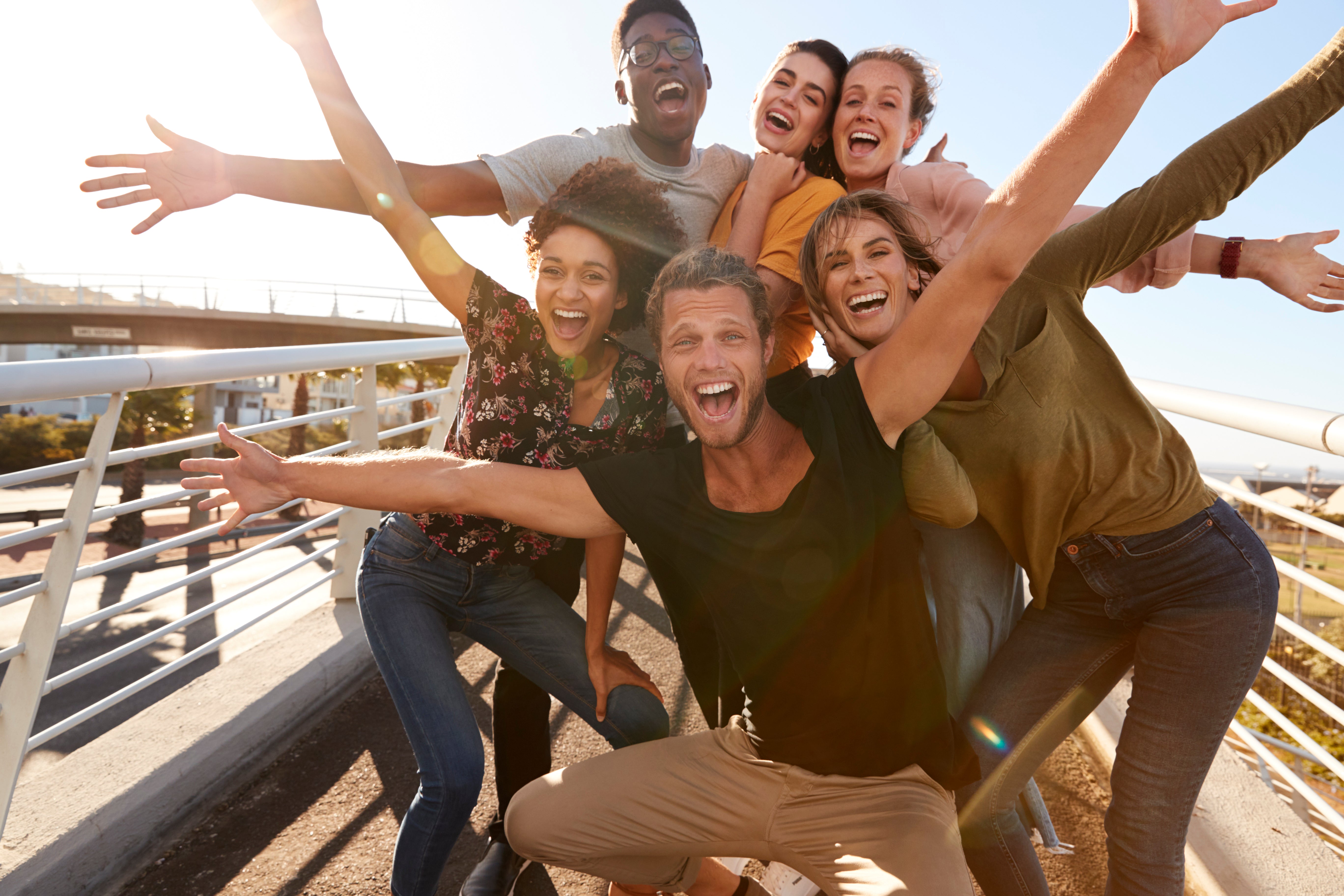 6 friends celebrating with arms raised in the air to celebrate customer purchase.